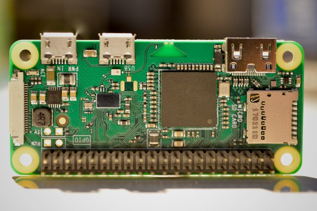 A close-up of a Raspberry Pi Zero single-board computer showing its micro USB ports, mini HDMI port, microSD card slot, and GPIO pins on a blurred background.