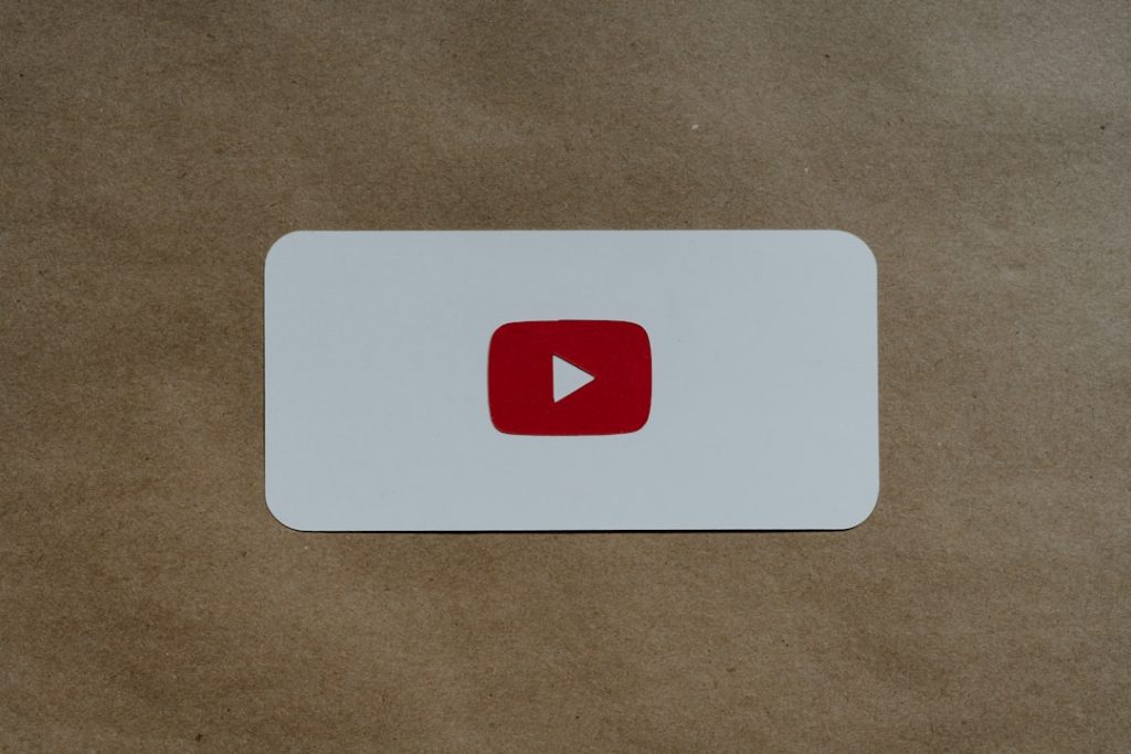 A rectangular white card with the red YouTube play button logo is placed on a brown paper background.
